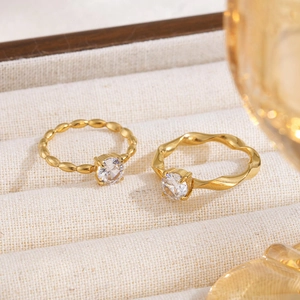 Elegant gold Moebius rings with cubic zirconia on a vintage beige jewelry tray