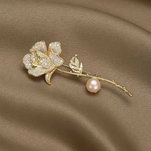 Détail d'une broche rose avec pavé de zircons et perle rose sur satin doré