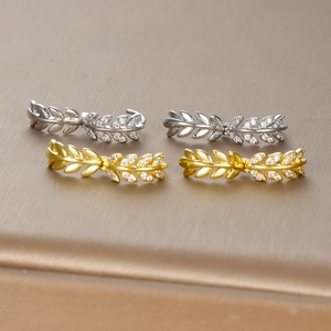 Macro view of olive leaf stud earrings with clear zircons in gold and silver finish
