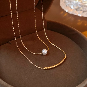 Close-up of a double-layered baroque pearl necklace inside a brown velvet jewelry case