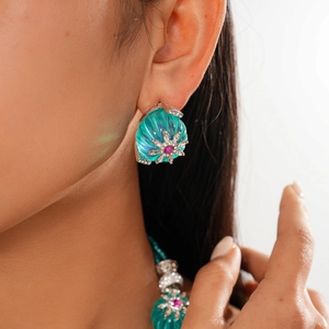 Close-up of vintage flower earrings with turquoise resin, pink gem, and silver details