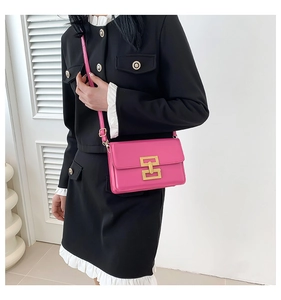 Close-up of pink leather crossbody bag featuring a golden rectangular lock and strap