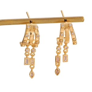 Macro detail of gold layered tassel earrings with white zircon stones and fringe elements