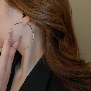 Close-up of model wearing large minimalist silver polished metal hoop earrings