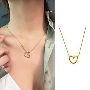 Gold twisted heart pendant necklace with fine snake chain displayed on a female model