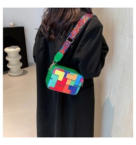 Detail view of a green crossbody bag with colorful geometric patterns and wide strap
