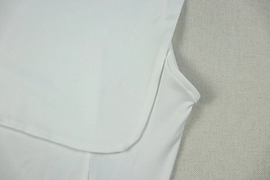 Detail of double-needle stitching on the neckline of a white chiffon mini dress