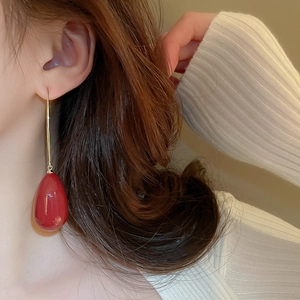 Gros plan d'élégantes boucles d'oreilles perles gouttes rouges avec crochet doré