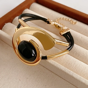 Detailed shot of black gold leather bracelet with oval black gemstone and gold metal