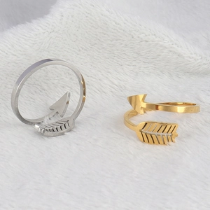 Detailed view of adjustable gold and silver arrow rings on white textured background