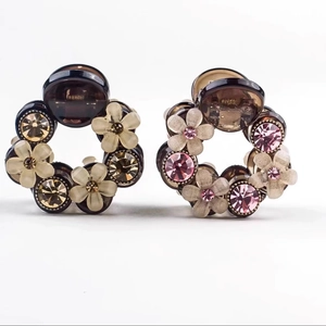 Detailed close-up of camellia flower hair clips with sparkling crystals and resin finish