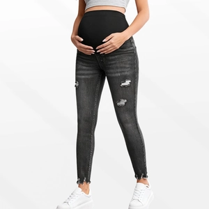 Close-up of maternity jeans showing elastic belly support and distressed rip details