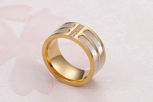 Close-up of wide gold-plated ring featuring white shell inlay and zircon accents