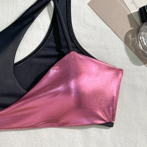 Detail shot of bikini top with contrast of black matte fabric and pink metallic finish