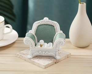 Detailed view of vintage European mini sofa jewelry rack holding a gold pearl ring
