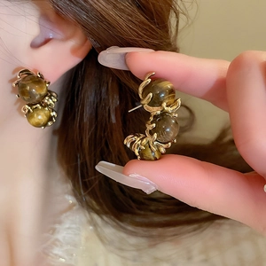 Close-up of vintage Maillard tiger eye stone earrings with intricate gold spiral metal wrap