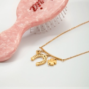 Detail of horseshoe and four-leaf clover charms on a gold clover lucky necklace