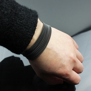 Detail of 1.7mm stainless steel wire coil bracelet in deep black finish on wrist