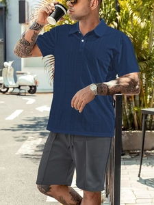 Detail of navy waffle textured polo shirt and grey shorts on a male model outdoors