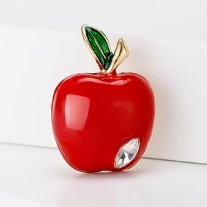 Golden red apple brooch with green enamel leaf and crystal accent on white background