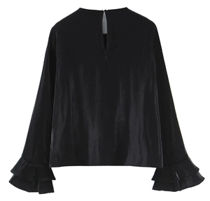Detail of ruffled cuffs and glossy satin fabric on a black long sleeve blouse