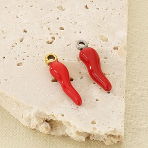 Macro detail of red chili pepper pendants with gold and silver loops on stone