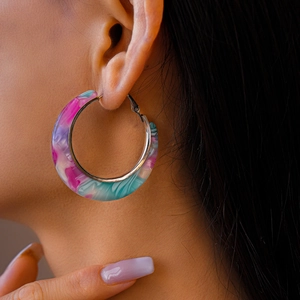Close-up of model wearing colorful marble-pattern acetate C-shape hoop earrings