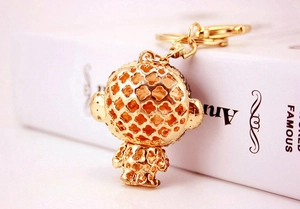 Detailed close-up of golden rhinestone monkey keychain with intricate hollowed flower patterns