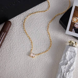 Close-up of golden paperclip chain necklace with sparkling zircon pendant in a chic setup