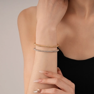 Close-up of gold and silver twisted cable metal cuff bracelets on a female wrist