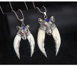 Detail of two silver wolf tooth necklaces with red and blue gemstone eyes and bone-like resin