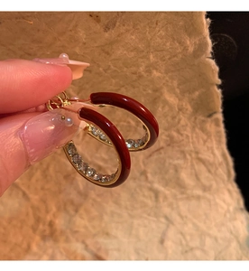 Detail of C-shaped earrings with burgundy enamel coating and sparkling inner rhinestones