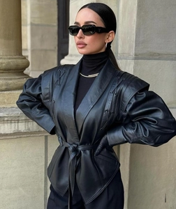 Détail d'une veste chic en similicuir noir avec manches bouffantes et ceinture à la taille