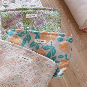 Detailed view of woven jacquard makeup bags in three vintage floral and geometric patterns