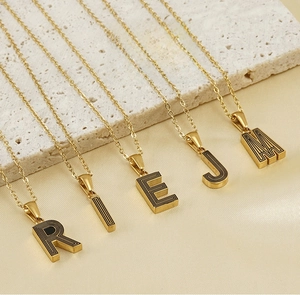 Détail des pendentifs lettres R I E J M plaqués or 18k sur un fond de soie