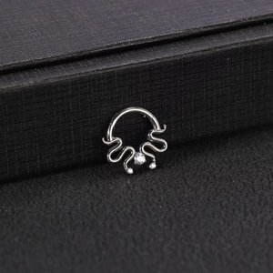 Dettaglio del piercing Medusa in titanio G23 con tre zirconi brillanti su una scatola porta gioie
