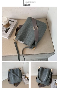 Close-up of crocodile embossed bucket bag in blue with a wide woven shoulder strap