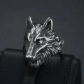 Detailed view of vintage silver wolf head ring on black leather textured display