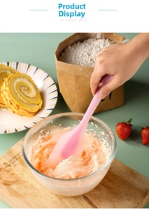 Pink silicone spatula mixing cream in a glass bowl during a home baking session