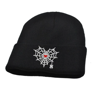 Detail of gothic heart spider web embroidery and small spider pendant on black knit beanie