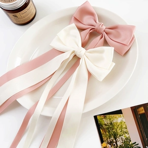 Detail of pink and beige satin bow hair clips with ribbons on a ceramic plate