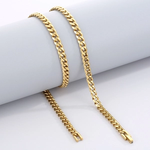 Detail of a golden Cuban link necklace with a box clasp on a gray cylindrical display