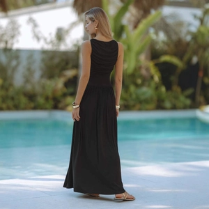 Elegante abito lungo nero senza maniche arricciato, mostrato a bordo piscina stile resort