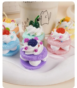 Makroansicht bunter Mini-Kuchenanhänger mit realistischen Sahneblumen und Fruchtmotiven