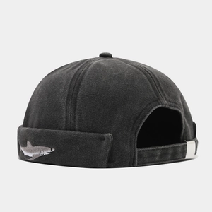 Detail of shark embroidery and adjustable metal buckle on washed cotton docker cap