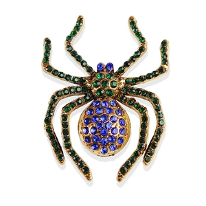 Macro detail of vintage gold spider brooch with vibrant blue and green crystal stones