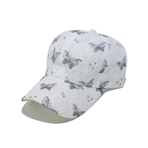 Detail of white lace baseball cap featuring grey butterfly prints and mesh texture