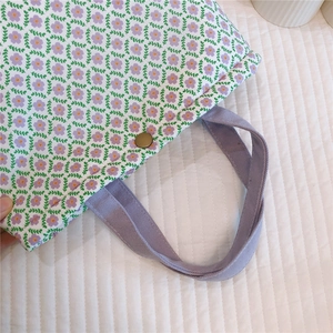 Close-up of floral cotton canvas tote with purple fabric handles and bronze metal snap button