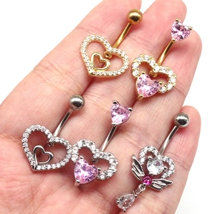 Selection of heart-shaped belly rings with pink and clear crystals held in hand