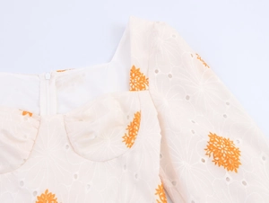 Detalle del escote cuadrado con bordado calado y estampado floral naranja en blanco